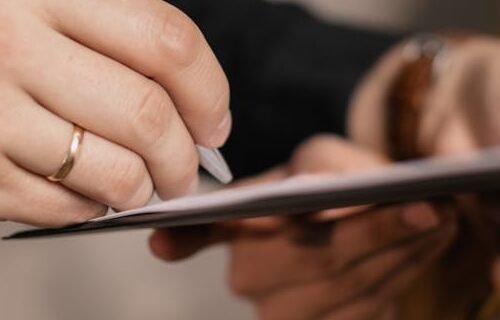 Close-up of two professionals signing a business document, emphasizing collaboration and negotiation.